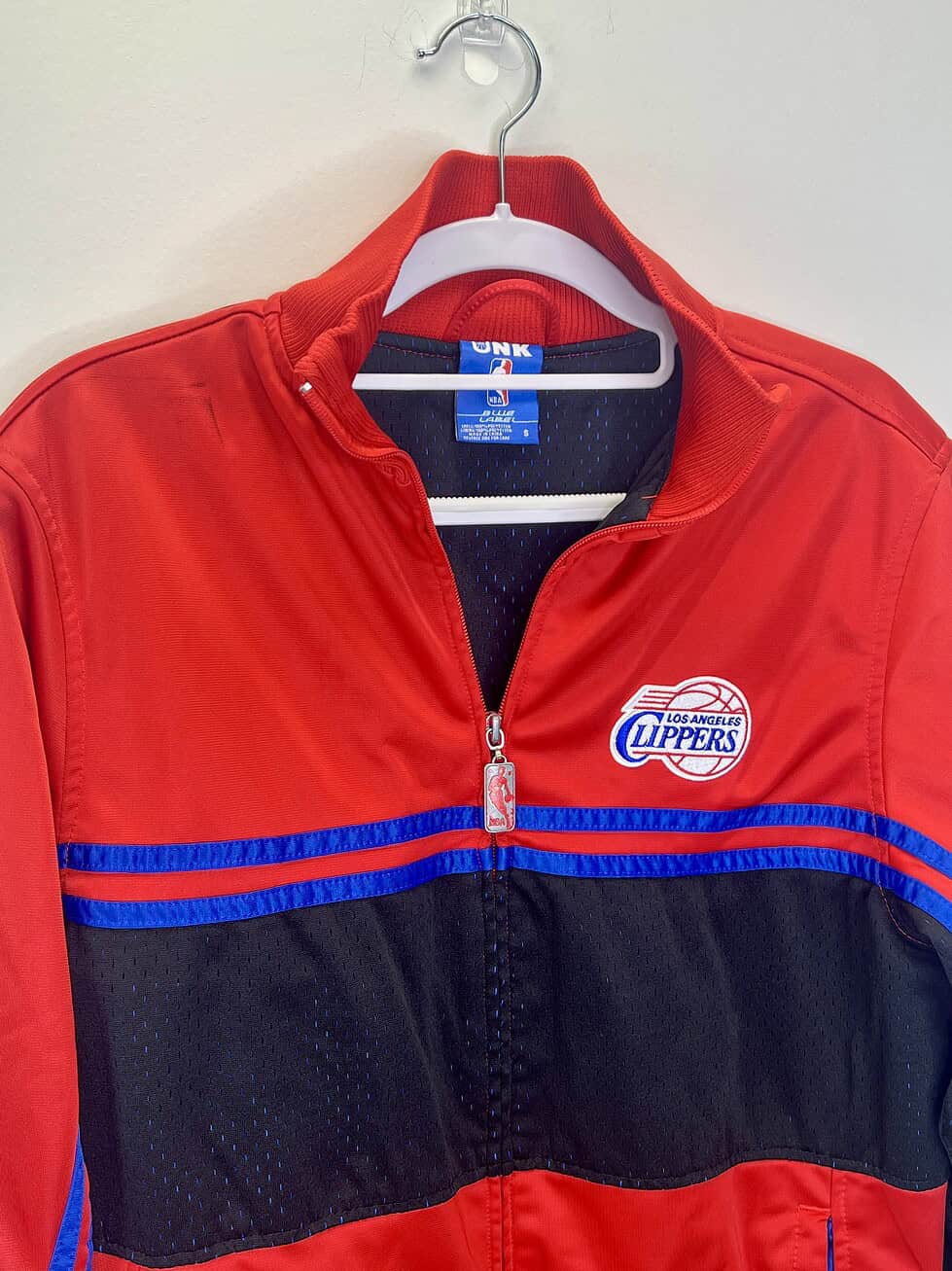 vintage-style Los Angeles Clippers red and black zip-up jacket with blue accents, NBA logo zipper pull, and mesh detailing.