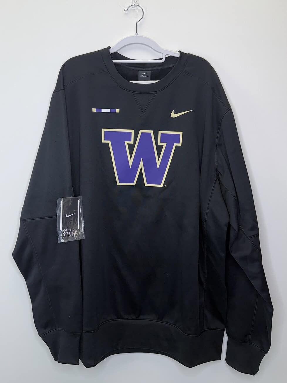 Front and back views of a black Washington Huskies Nike Dri-FIT sweatshirt with gold swoosh and official on-field tag, size 2XLT.